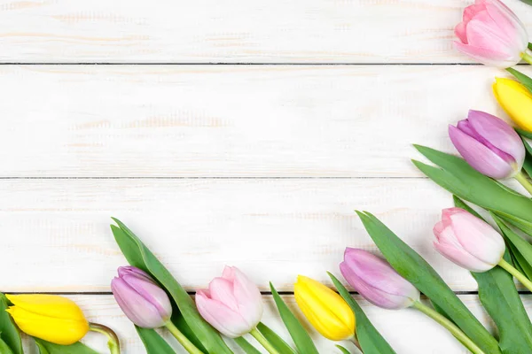 Bando de tulipas rosa e amarela deitadas sobre um fundo de madeira branco — Fotografia de Stock