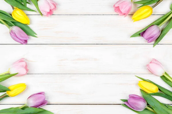 Bando de tulipas rosa e amarela em um fundo de madeira branco — Fotografia de Stock