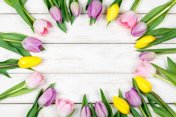 Bando de tulipas rosa e amarela em um fundo de madeira branco — Fotografia de Stock