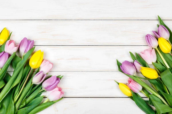 Bando de tulipas rosa e amarela em um fundo de madeira branco — Fotografia de Stock