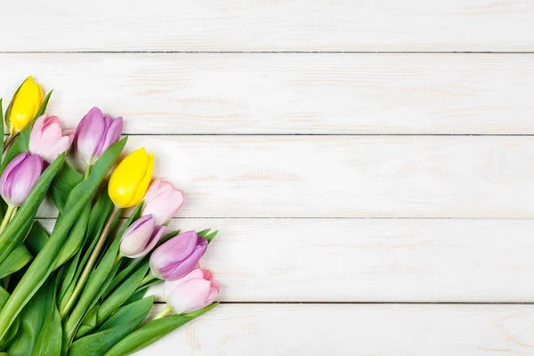 Bando de tulipas coloridas em um fundo de madeira branco — Fotografia de Stock