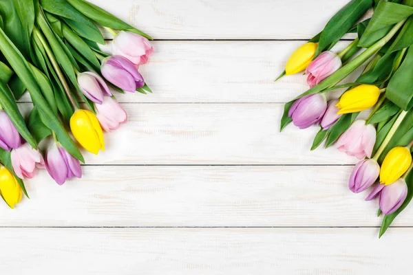 Bando de tulipas rosa e amarela em um fundo de madeira branco — Fotografia de Stock