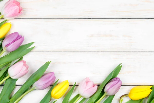 Bando de tulipas rosa e amarela deitadas sobre um fundo de madeira branco — Fotografia de Stock