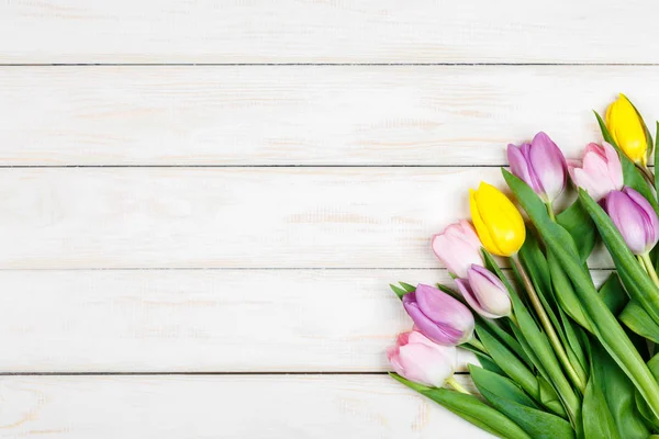 Bando de tulipas coloridas em um fundo de madeira branco — Fotografia de Stock