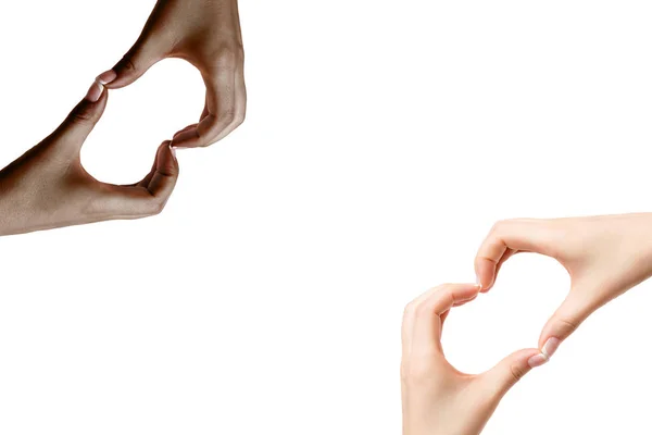 African and white woman's hands show symbol of heart on white ba — Stock Photo, Image