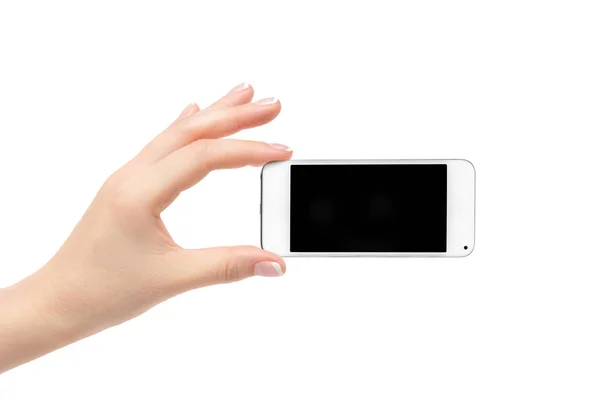 La mano della donna tiene un telefono bianco su uno sfondo bianco . — Foto Stock