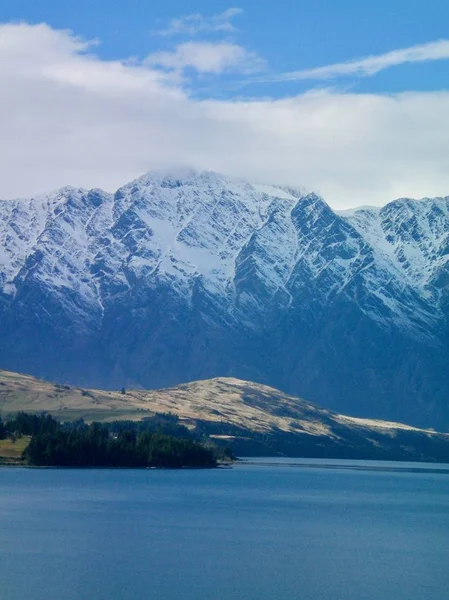 Montanhas nevadas subindo acima de um lago azul — Fotografia de Stock