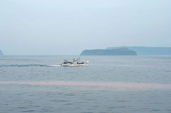 Рибальський човен, що проходить деякі острови, з водоростями рожевого кольору з водоростей . Стокова Картинка