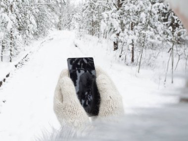 Kız yün eldiven bir cep telefonu tutuyor