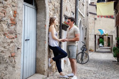 Güzel genç çift ayakta eski kalenin eski duvarları yakınında taş bir yolda