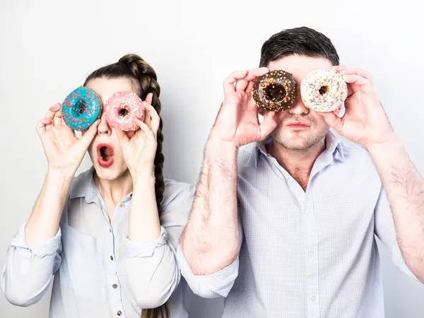 Couple drôle avec beignets colorés — Photo