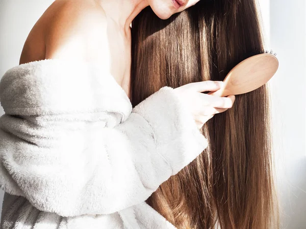 Linda, joven mujer peinándose el pelo — Foto de Stock