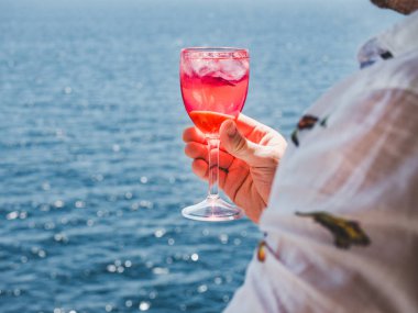 Elinde güzel bir kadeh pembe şarap tutan adam