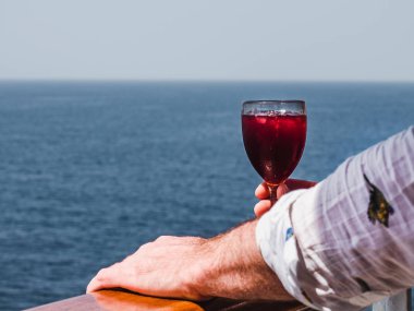 Elinde güzel bir kadeh pembe şarap tutan adam