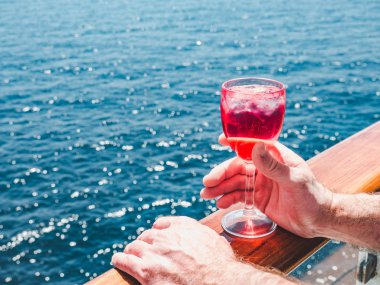 Elinde güzel bir kadeh pembe şarap tutan adam