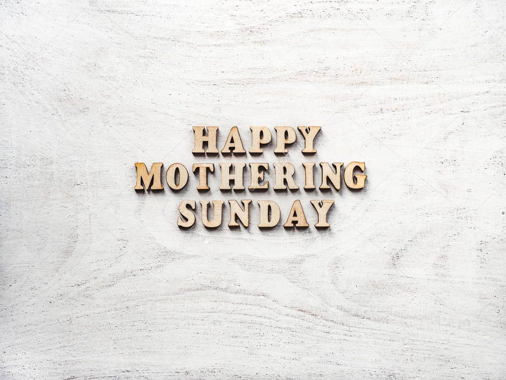 Wooden letters of the alphabet in the form of the words Mothering Sunday lying on the table. View from above. Isolated background, wooden surface. Congratulations for relatives, friends, colleagues