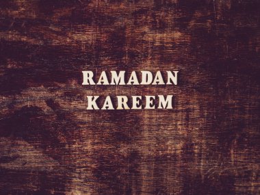 Alfabenin tahta harfleri masanın üzerinde duran RAMADAN KAREEM şeklinde. Güzel kart. İzole arka plan, ahşap yüzey. Akrabalar, arkadaşlar, meslektaşlar için tebrikler.