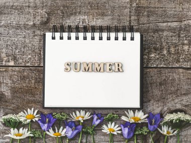 Güzel, parlak çiçekler beyaz, ahşap bir masanın üzerinde yatıyor. Yukarıdan görüntüle, yakın plan