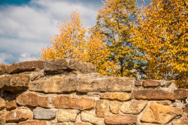 Güçlü taş duvar ve sarı sonbahar yaprakları