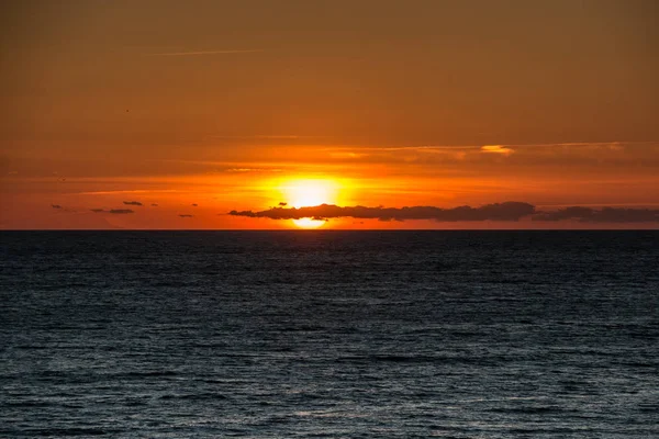 Sonnenuntergang und schwarzes Wasser am dunklen Strand von Spanien — Stockfoto