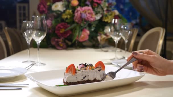 Interior del restaurante. San Valentín. El cierre del plato con la torta de crema con la fresa y otras bayas. La mano femenina con un tenedor rompe un trozo. Disparo en 4k — Vídeos de Stock