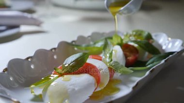 Sağlıklı gıda ve vejetaryen kavramı. Boşalırcasına zeytinyağı caprese salatası kapatın. Mozzarella peyniri ile İtalyan caprese salatası. Ağır çekim
