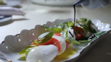 Sağlıklı gıda ve vejetaryen kavramı. Boşalırcasına sirke caprese salatası kapatın. Mozzarella peyniri ile İtalyan caprese salatası. Ağır çekim