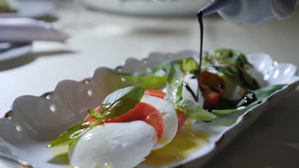 Comida saludable y concepto vegetariano. Primer plano de verter vinagre sobre ensalada caprese. Ensalada caprese italiana con queso Mozzarella. Movimiento lento — Vídeos de Stock