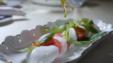 Sağlıklı gıda ve vejetaryen kavramı. Boşalırcasına zeytinyağı caprese salatası kapatın. Mozzarella peyniri ile İtalyan caprese salatası. Ağır çekim