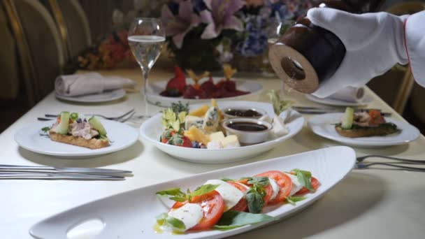 건강 한 음식과 채식 개념입니다. 닫기 요리사 손의 향신료와 고추 caprese 샐러드에 추가. 모 짜 렐 라 치즈와 이탈리아 caprese 샐러드입니다. 슬로우 모션 — 비디오