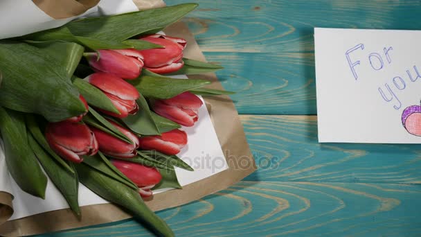 トップのビュー、メッセージ メモと木製のテーブル チューリップ花の花束のため。カップルの関係というコンセプト。聖バレンタインの s 日。4 k で撮影します。 — ストック動画