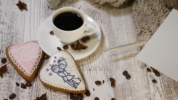 Un par de relaciones. Concepto de San Valentín. Una taza de café y galletas de jengibre con aguja de tejer e hilo sobre fondo de madera. mano pone para usted nota de mensaje, tiro en 4k — Vídeo de stock