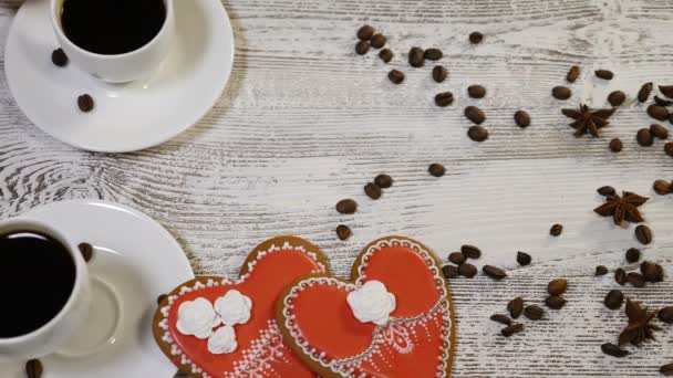 Duas relações. Conceito do Dia de São Valentim. Vista superior de duas xícaras de café realizadas por mãos femininas e masculinas com biscoito de gengibre em forma de coração no fundo de madeira. Tiros em 4K — Vídeo de Stock