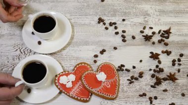 Çift ilişkiler. St Sevgililer günü kavramı. İki bardak kahve üstten görünüm erkek tarafından düzenlenen ve kalp ile erkek el ahşap arka plan üzerinde zencefilli bisküvi şeklinde. 4 k'dan fazla vurdu