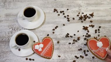 Çift ilişkiler seviyorum. St. Valentine kavramı. İki bardak kahve ve kalp üstten görünüm kahve çekirdekleri ile ahşap arka plan üzerinde zencefilli bisküvi şeklinde. Başka bir kalp şeklinde el koyar
