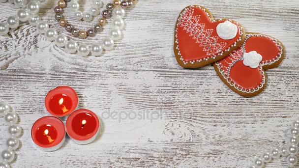Fondo del Día de San Valentín. Dos galletas de jengibre en forma de corazón, velas de té y perlas sobre fondo de madera. Llama de vela moviéndose en el viento. Concepto de relaciones de pareja. Disparo en 4k — Vídeos de Stock