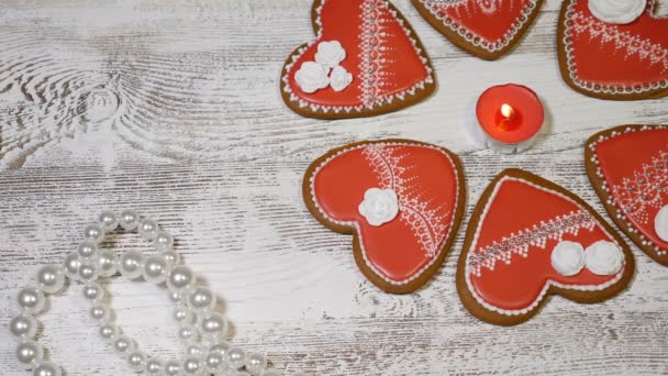 Pár vztahů koncept. Svatého Valentýna pozadí. Zázvorové sušenky, hořící svíčkou a perle na dřevěné pozadí ve tvaru srdce. Snímek v rozlišení 4k — Stock video