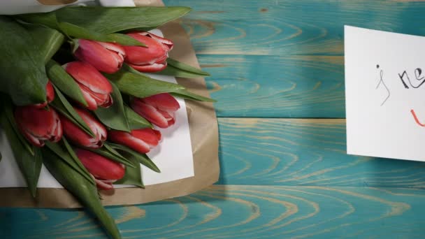 Draufsicht auf einen I-need you message note und Tulpenblumenstrauß auf einem Holztisch. Liebesbeziehungskonzept. Valentinstag. Schuss in 4 k — Stockvideo