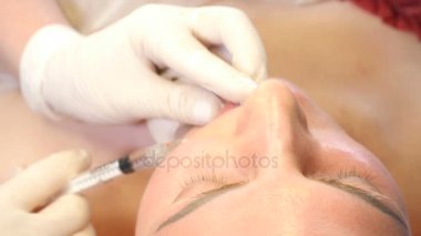 Güzellik Kliniği kavramı. Ten welness yakın çekim yapma botox enjeksiyon için kadın dudaklar eller. Genç kadın yüz enjeksiyon etmek alır... Yüz gençleştirme. 4k
