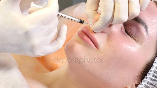 Conceito de clínica de beleza. Close-up de mãos esteticistas fazendo injeção de botox em lábios e nariz femininos. Uma jovem recebe um procedimento de injecção facial, um rejuvenescimento facial. 4k — Vídeo de Stock