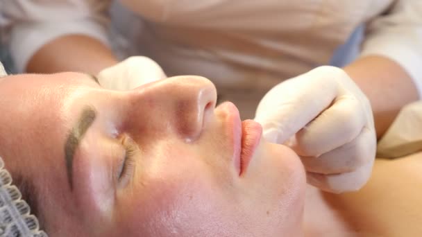 Concept de clinique de beauté. Gros plan des mains d'esthéticienne faisant l'injection de botox aux lèvres féminines. Jeune femme obtient une procédure d'injection faciale.. rajeunissement du visage. 4k — Video