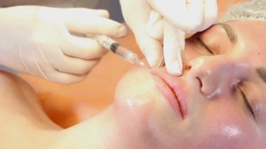 Güzellik Kliniği kavramı. Ten welness yakın çekim yapma botox enjeksiyon için kadın dudaklar eller. Genç kadın yüz enjeksiyon etmek alır... Yüz gençleştirme. 4k