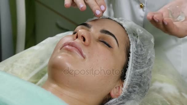 Concepto de clínica de belleza. Primer plano de la crema de difusión esteticista antes del procedimiento facial. Jovencita. Rejuvenecimiento facial. 4k — Vídeos de Stock