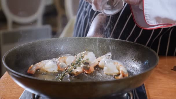 Primer plano de un chef que prepara un plato estilo Flambe en una sartén. En cámara lenta. El aceite y el alcohol se encienden con llamas abiertas. Cocinar y salar camarones tigre. Disparo en 4k — Vídeos de Stock