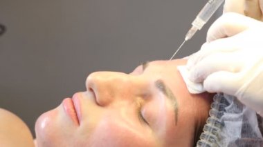 Güzellik kliniği. Eldiven giymiş güzellik uzmanları kadın derisine yüz yaşlanma enjeksiyonu yapıyor. Bir kadın güzellik yüz kozmetolojisi prosedürünü uygular. Botoks. Kolajen enjeksiyonları. 4K 'da çekilmiş.
