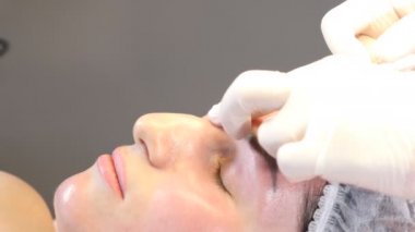 Güzellik kliniği. Eldiven giymiş güzellik uzmanları kadın derisine yüz yaşlanma enjeksiyonu yapıyor. Bir kadın güzellik yüz kozmetolojisi prosedürünü uygular. Botoks. Kolajen enjeksiyonları. 4K 'da çekilmiş.