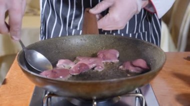 Şef yemek Flambe tarzı ile yemek restoran sıcak bir tava üzerinde karaciğer dilim close-up. Kaşıkla karıştırarak. Ağır çekim.