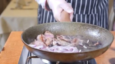 Şef yemek Flambe tarzı ile yemek restoran sıcak bir tava üzerinde karaciğer dilim close-up. Çanak ile tavada karıştırarak. Ağır çekim.