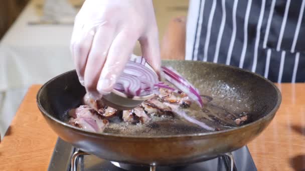 Primo piano del piatto Chef Cooking Flambe Style con fette di fegato su una padella calda nel ristorante. mano nella mano guanto mette cipolla a padella. Rallentatore . — Video Stock