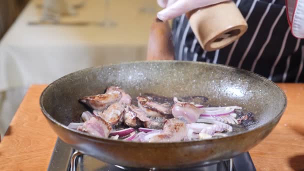 Primo piano del piatto Chef Cooking Flambe Style con fette di fegato su una padella calda nel ristorante. mano nel guanto aggiunge pepe al piatto in padella. Rallentatore . — Video Stock